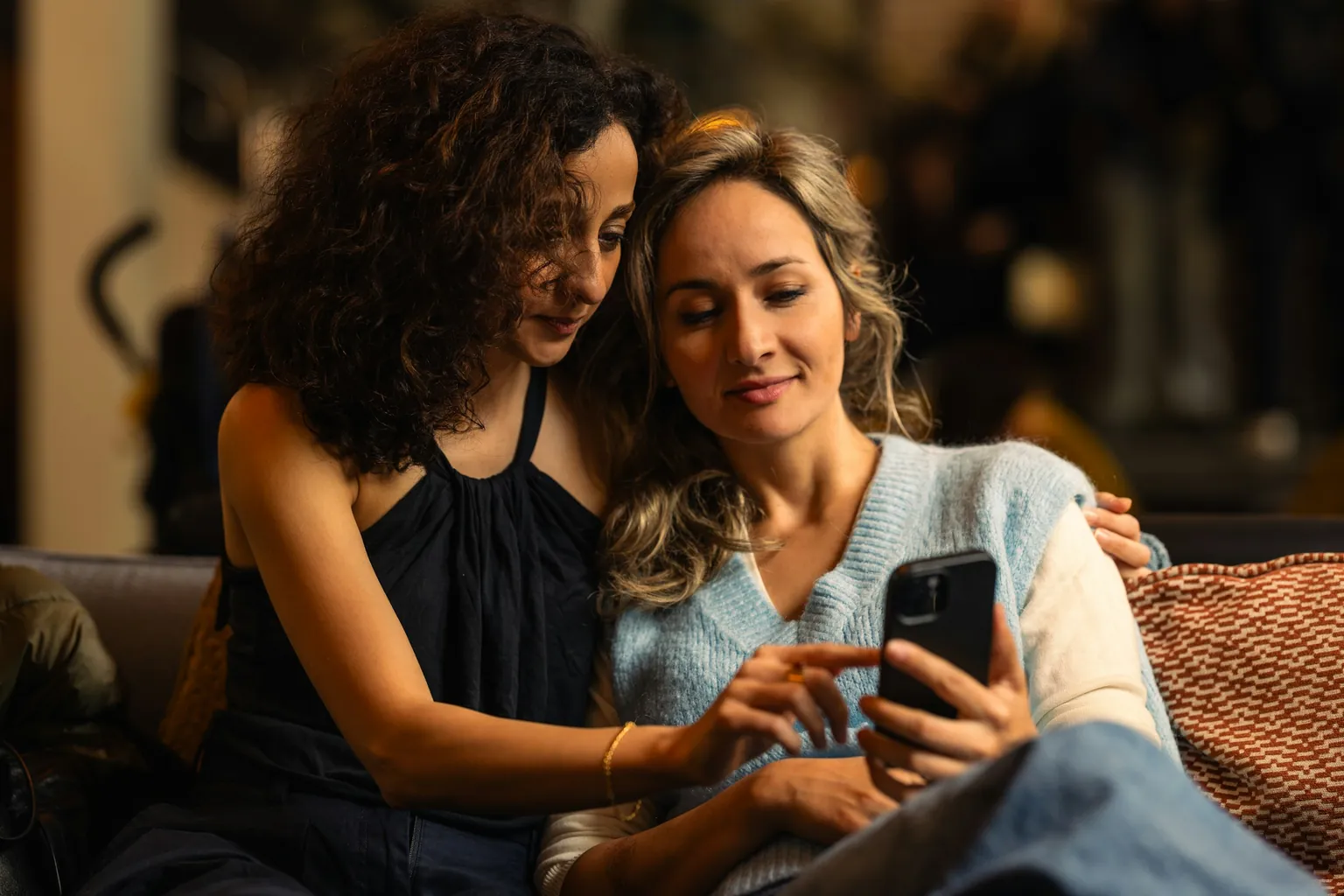 Two friends on a sofa reading a listing on one phone